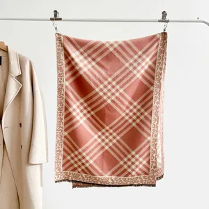 Detail of pink plaid scarf with leopard print edges and soft fringe on white coat rack