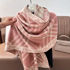 Detailed view of the soft fringe edges and jacquard check pattern on the pink knit shawl