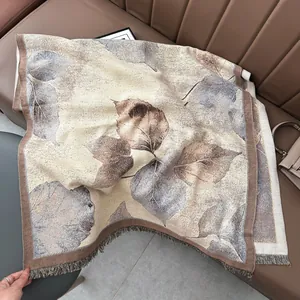 Close-up of thick jacquard shawl with brown leaf pattern and fringed edges on sofa