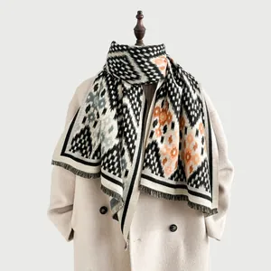 Détail d'une écharpe en maille à fleurs et losanges avec franges sur manteau beige