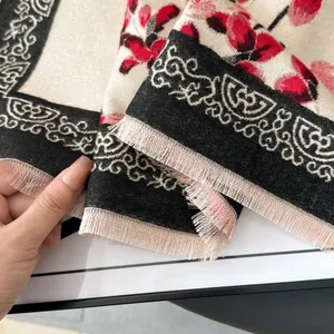 Detalle macro de bufanda con estampado de flores de ciruelo y bordes negros con flecos