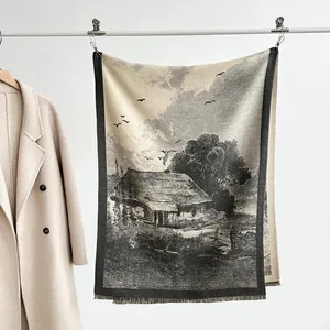 Detail of landscape knit scarf showing a rustic house scene and soft tassel edges