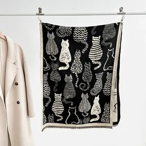 Detail of soft black and white cat pattern scarf featuring fine fringe and chic jacquard