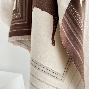 Dettaglio del motivo a cavallo e delle morbide frange sulla sciarpa marrone effetto cashmere