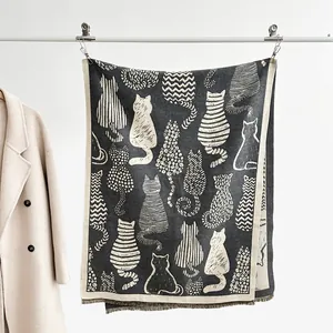 Detailed view of cat pattern scarf with black and white artistic silhouettes and tassels
