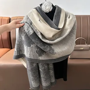 Detail of grey and beige jacquard cashmere-feel scarf with abstract patterns and tassels