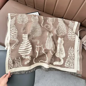 Detailed view of cat pattern knit scarf with soft tassels on a brown leather sofa