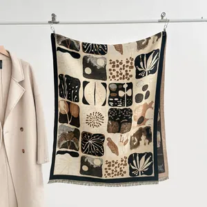 Detail of cashmere-like scarf showing abstract palm leaf prints and fringe hem