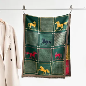 Detail of soft green scarf featuring colored horse patterns and tassel hem on display