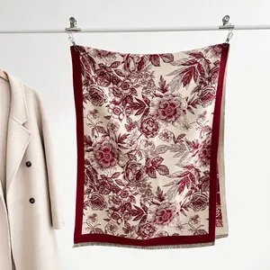 Detail of burgundy floral cashmere scarf showing delicate tassels and toile pattern