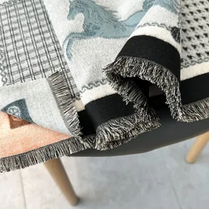 Detailed close-up of jacquard knit horse pattern scarf with fringe edges and thick texture