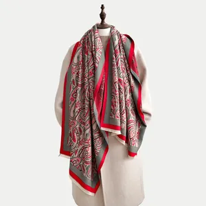 Winter paisley jacquard shawl scarf with red border and fringe on a beige coat model