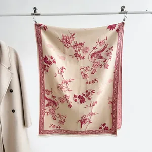 Dettaglio di sciarpa beige con motivi floreali cinesi rossi e frange sottili