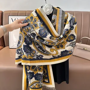 Vue détaillée d'un châle jacquard à motif paisley jaune drapé sur un pull noir