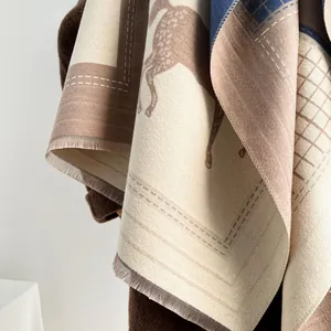 Dettaglio della sciarpa con stampa a cavalli, frange sottili e texture tipo cashmere
