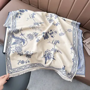 Dettaglio di motivi floreali con uccelli e frange corte sulla sciarpa pashmina color crema