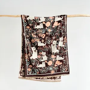 Close-up of knit scarf showing vintage cat patterns, floral motifs and fringed edges
