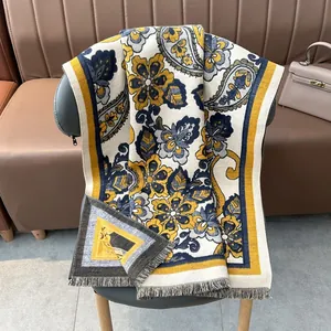 Châle épais jacquard paisley effet cachemire avec pompons sur une chaise moderne