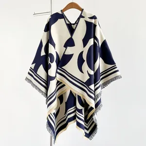 Détail du poncho en tricot bleu marine avec bordure au point de croix et franges longues