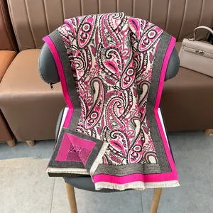 Pink paisley jacquard pashmina shawl with fringes draped on a grey chair