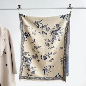 Dettaglio dello scialle etnico beige con stampe di fenice blu scuro e nappe sottili