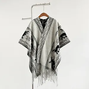 Detail eines Vintage-Strickponchos mit Rentiermotiven und langen Fransen auf weißem Grund