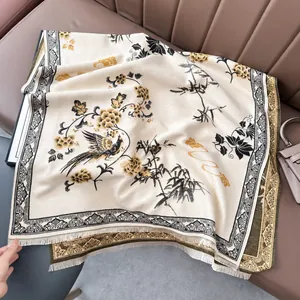 Dettaglio della sciarpa crema con stampe di fenice dorata e bordi con frange