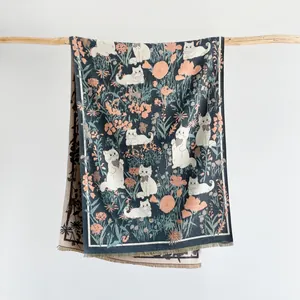 Detailed knit texture and tassels of a warm scarf featuring cat and floral patterns