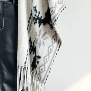 Detailaufnahme des ethnischen Strickschals mit grauen Jacquardmustern und langen weißen Fransen