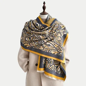 Close-up of thick paisley jacquard scarf with yellow and navy patterns and tassel fringe