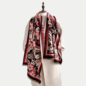 Détail du motif paisley sur écharpe en cachemire avec bordures rayées rouges et noires