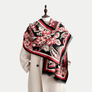 Vue détaillée d'un châle à motifs cachemire et franges sur un manteau blanc chic