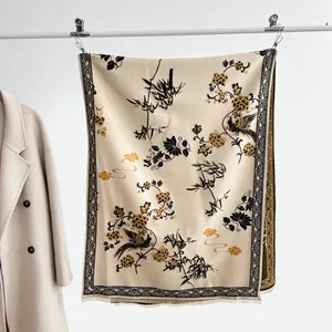 Dettaglio di pashmina beige con motivi floreali neri e bordi con morbide frange