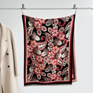 Détail d'un châle cachemire à motif paisley rouge et noir avec texture et franges