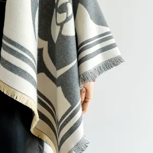 Détail du motif floral camélia sur un poncho épais en faux cachemire avec franges