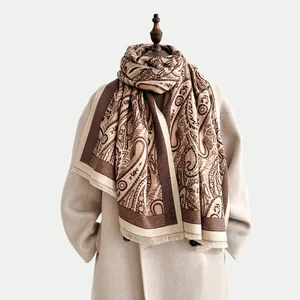 Detail view of winter scarf featuring brown paisley patterns and delicate fringed edges