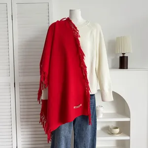 Détail d'une écharpe rouge effet cachemire avec de longues franges sur un pull blanc