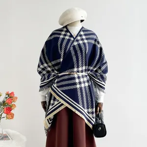 Detail of plaid cashmere poncho with soft tassels and slim white waist belt