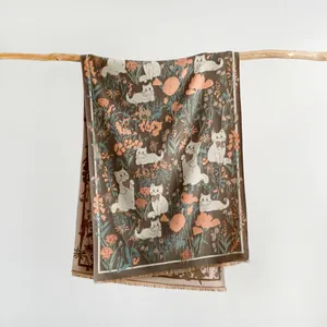 Detail of floral cat print scarf with fringe edges hanging on a natural wood branch