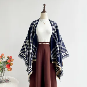 Detail of navy blue geometric cashmere-like poncho with star patterns and tassel hem