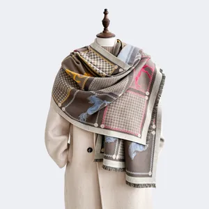 Detail of soft winter scarf featuring horse patterns, houndstooth weave and fine tassels