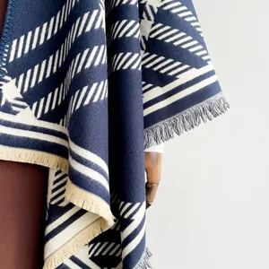 Detailed view of navy blue and white geometric jacquard pattern with tassel fringe edges