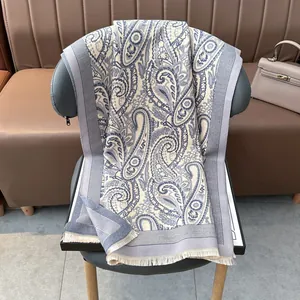 Classic paisley jacquard winter scarf in blue and white with fringe on a chair