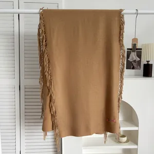 Détail de l'écharpe en cachemire camel foncé avec franges et étiquette tissée