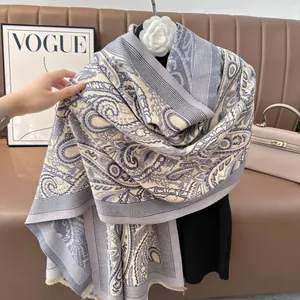 Detail of blue and beige paisley jacquard winter scarf featuring elegant fringe edges