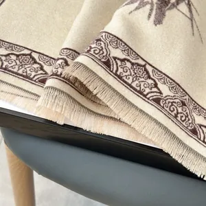 Dettaglio ravvicinato dello scialle pashmina beige con ricami floreali e nappe fini