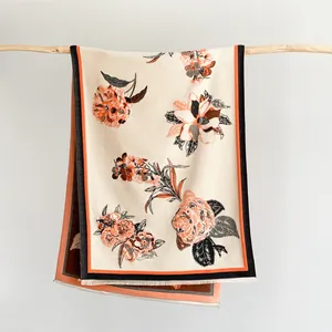 Detailansicht eines floralen Jacquard-Schals mit eleganten orangefarbenen Fransen