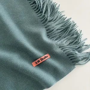 Détail de l'écharpe bleu Morandi avec texture douce, franges et étiquette rose