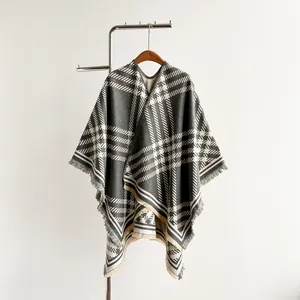 Detail of gray and white plaid cashmere poncho featuring soft fringe edges and thick texture