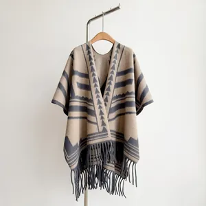 Details der beigen Strick-Poncho mit ethnischen Mustern und langen Quasten für Damen